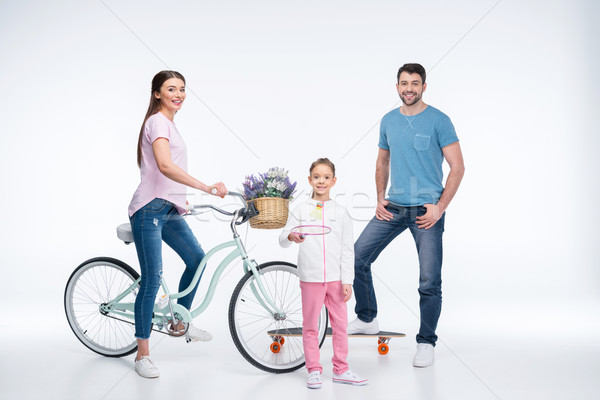 smiling family with skateboard, bicycle and badminton racket on white Stock photo © LightFieldStudios