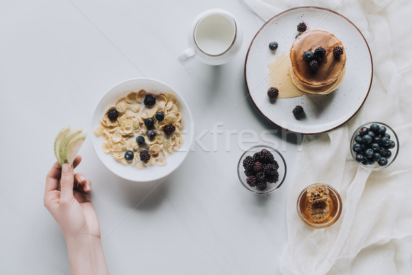 cropped shot of person eating healthy muesli and pancakes with fruits for breakfast on grey Stock photo © LightFieldStudios