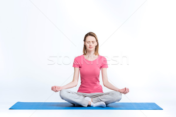 Sporty woman practicing lotus yoga position on mat on white Stock photo © LightFieldStudios