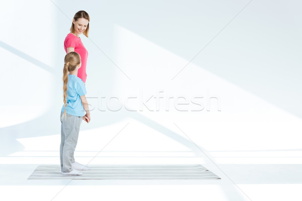 Happy mother and little daughter standing on yoga mat and looking at each other Stock photo © LightFieldStudios