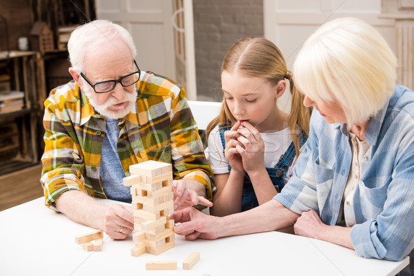 Concentrated little girl with grandparents playing jenga game together at home   Stock photo © LightFieldStudios