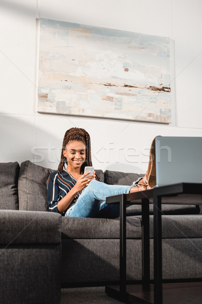 Сток-фото: женщину · смартфон · диване · счастливым · афроамериканец · домой