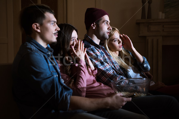 Stock photo: side view of scared friends watching movie with popcorn at home