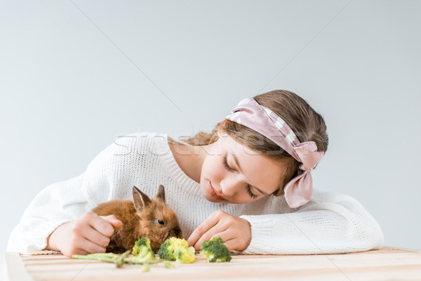 adorable girl feeding cute furry rabbit with broccoli at wooden table   Stock photo © LightFieldStudios