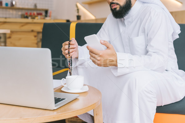 穆斯林 男子 工作的 射擊 智能手機 筆記本電腦 商業照片 © LightFieldStudios