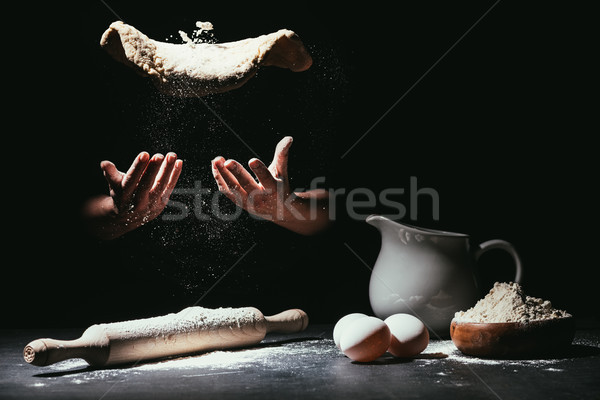 cropped shot of chef throwing up dough for pizza on black Stock photo © LightFieldStudios
