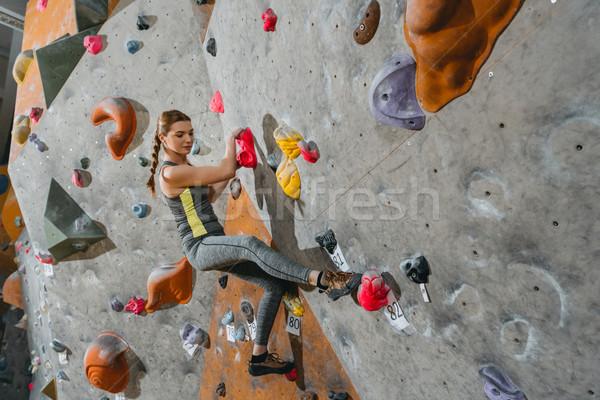 Stock photo: woman climbing wall with grips