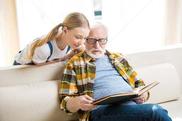 Cute little girl with grandfather in eyeglasses reading book together Stock photo © LightFieldStudios