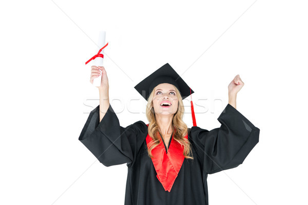 Young blonde woman in graduation gown holding diploma and triumphing on white  Stock photo © LightFieldStudios