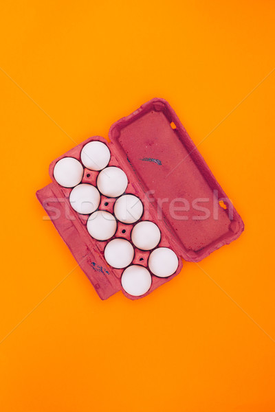top view of chicken eggs in violet egg tray isolated on orange Stock photo © LightFieldStudios