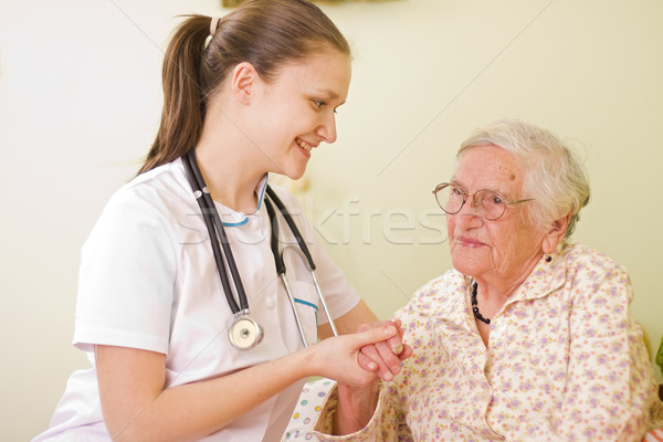 A young doctor / nurse visiting an elderly sick woman socialising - talking - with her, holding her  Stock photo © Lighthunter