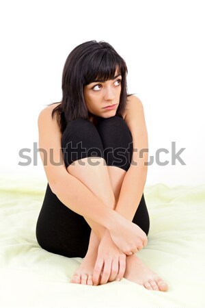Pretty young woman looking sadly at copyspace sitting on bed over white. Stock photo © Lighthunter