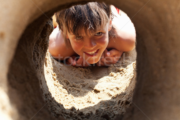 Happy boy on the beach looking through sand castle tunnel Stock photo © lightkeeper