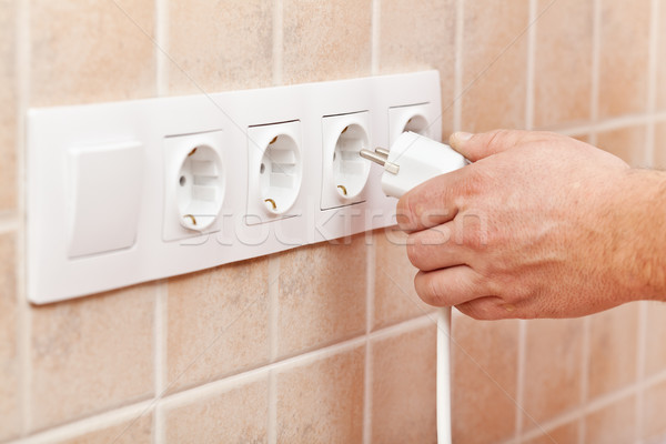 Male hand plugging power cord into electrical socket in the wall Stock photo © lightkeeper