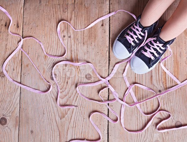 Stock photo: The problem - childs feet and long twisted shoelaces