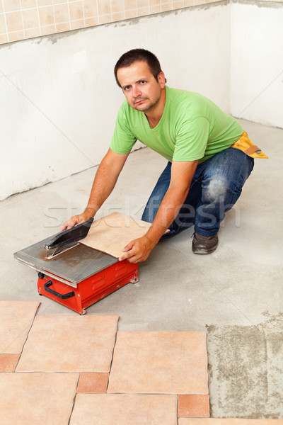 Man cutting ceramic floor tiles with electric cutter Stock photo © lightkeeper