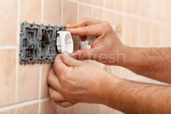 Electrician hands installing electrical wall fixture Stock photo © lightkeeper