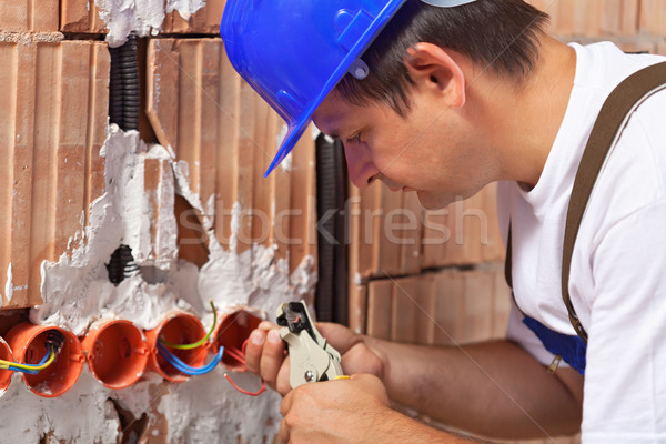 Stock photo: Worker installing electrical wires in building wall