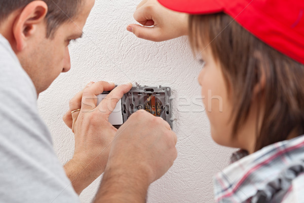Stock photo: Young boy watches as his father installs an electrical wall sock