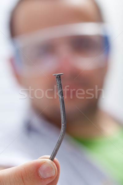 Stock photo: Man holding crooked nail - closeup on nail