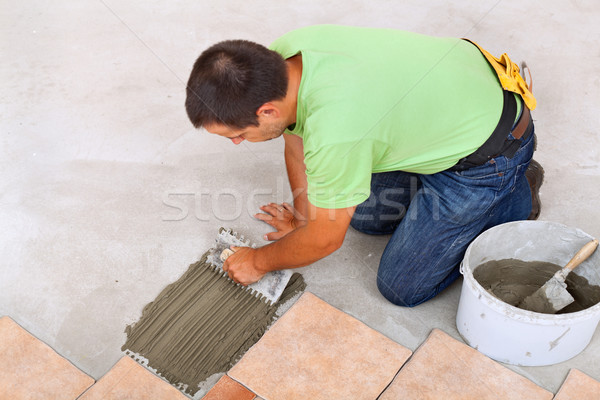 Man laying ceramic tiles floor - spreading the adhesive Stock photo © lightkeeper