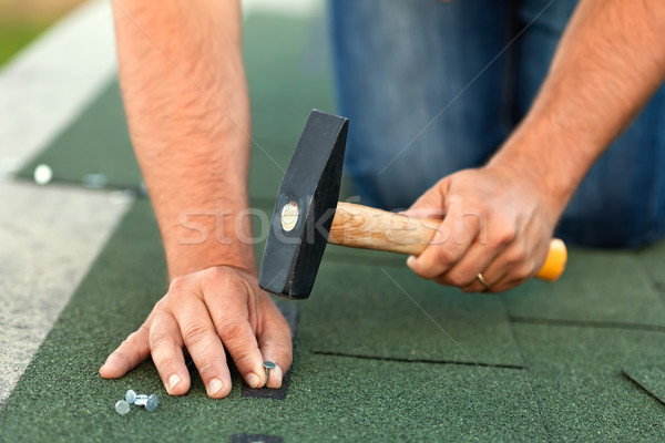 Stock photo: Worker hands installing bitumen roof shingles - horizontal crop