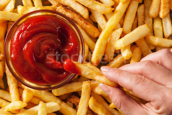 Hand dipping french fries in tomato sauce or ketchup Stock photo © lightkeeper
