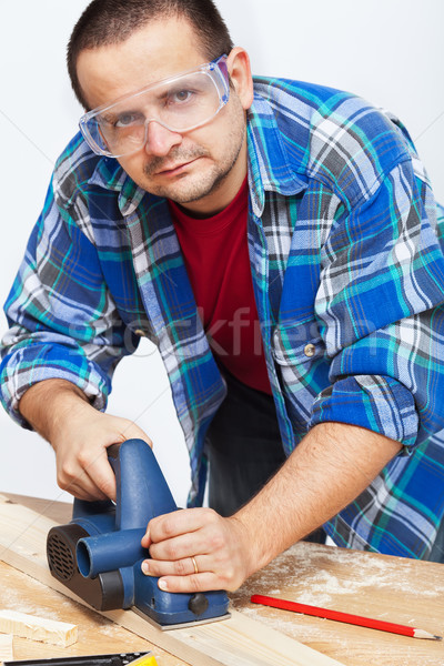 Carpenter or joiner working with electric planer Stock photo © lightkeeper