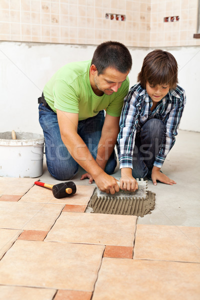 Boy learning how to spread adhesive for ceramic floor tiles Stock photo © lightkeeper