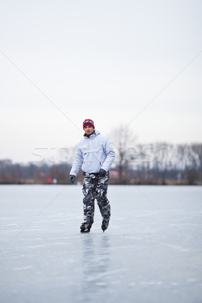 Handsome young man ice skating outdoors on a pond Stock photo © lightpoet