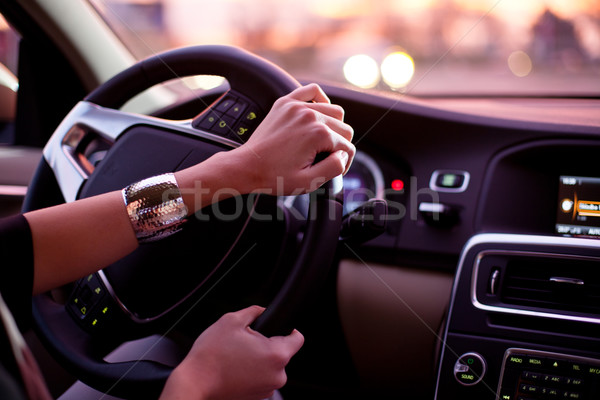 Stock photo: young woman driving her modern car at night in a city