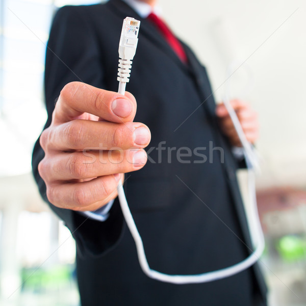 Young businessman holding an ethernet cable - stressing the impo Stock photo © lightpoet