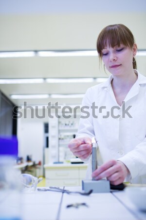 Pretty, female researcher using a microscope in a lab Stock photo © lightpoet