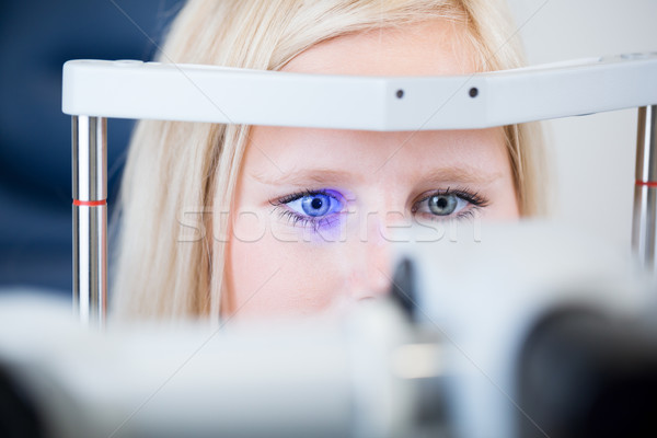 Pretty, young female patient having her eyes examined by an eye doctor Stock photo © lightpoet