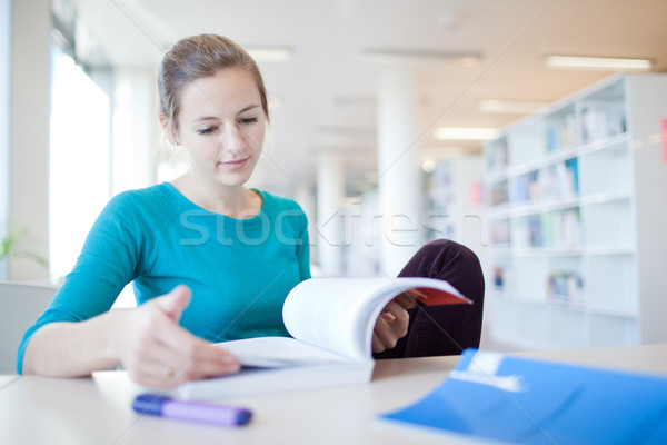 Stock photo: pretty young college student in a library (shallow DOF; color to