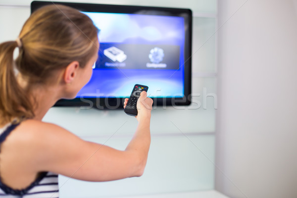 Young woman at home watching TV, turning it on, changing channel Stock photo © lightpoet
