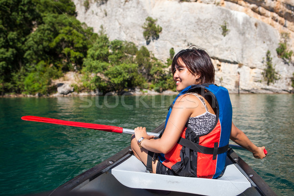 Stock photo: Pretty, young woman on a canoe on a lake, paddling