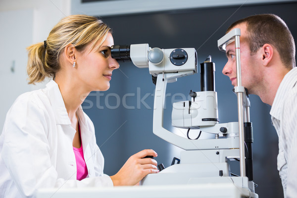 Handsome young man having his eyes examined by an eye doctor Stock photo © lightpoet