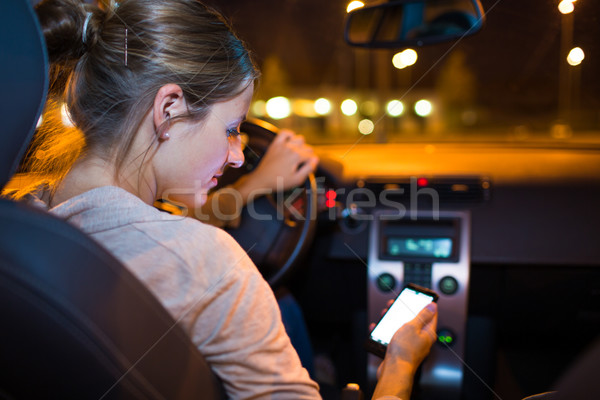 Pretty young woman using her smart phone while driving her car Stock photo © lightpoet
