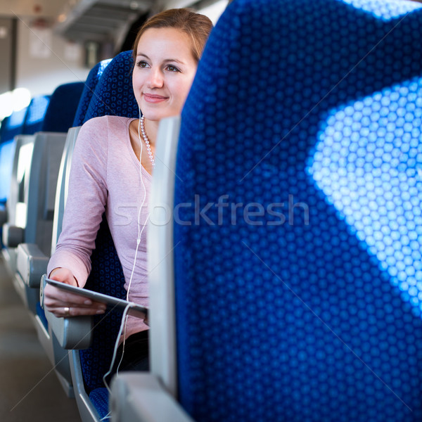 Stock photo: Young woman using her tablet computer while traveling by train
