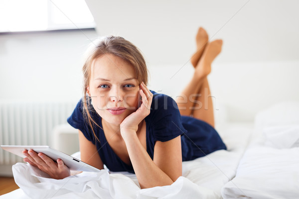 Pretty, young woman using her tablet computer in bed Stock photo © lightpoet