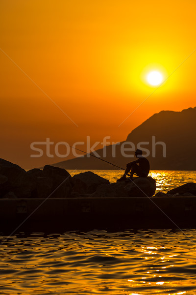 Fisherman's silhouette on the beach at colorful sunset Stock photo © lightpoet