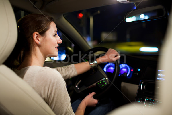 Stock photo: young woman driving her modern car at night in a city