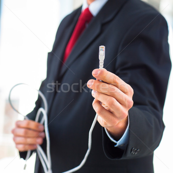 Young businessman holding an ethernet cable - stressing the impo Stock photo © lightpoet