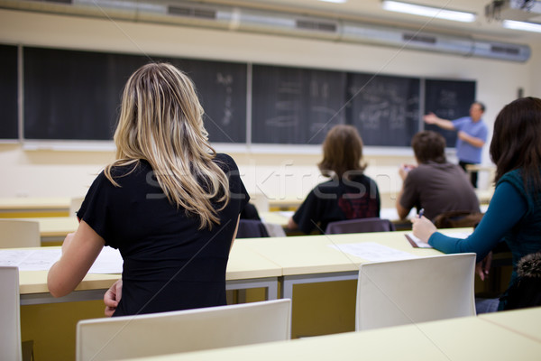Stock photo: young pretty female college student sitting in a classroom full 