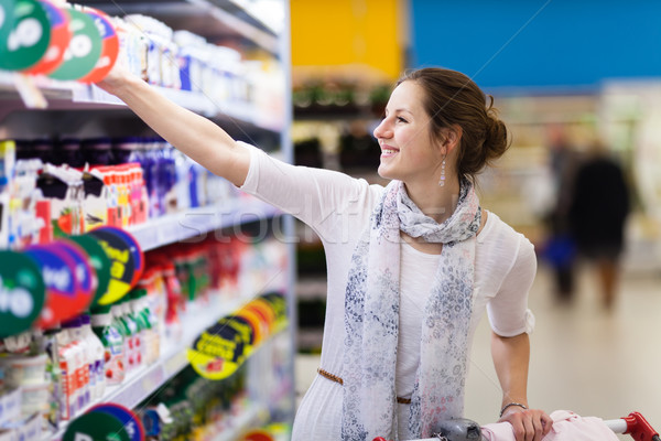 Stock photo: Beautiful young woman shopping for diary products