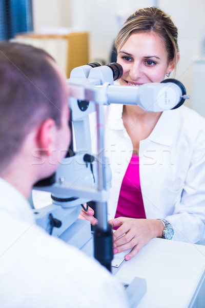 Handsome young man having his eyes examined by an eye doctor Stock photo © lightpoet