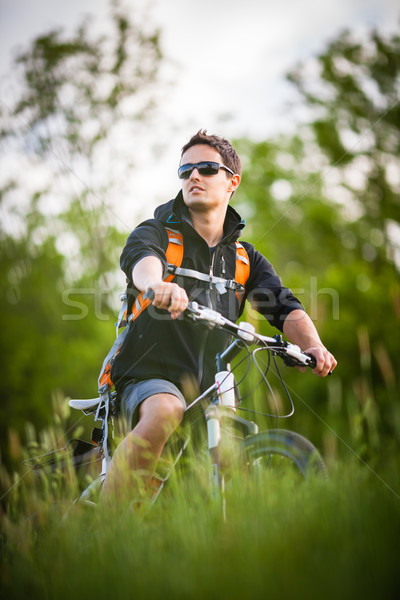 Handsome young man biking in the countryside Stock photo © lightpoet