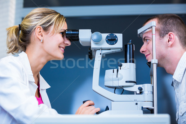 Stock photo: Handsome young man having his eyes examined by an eye doctor