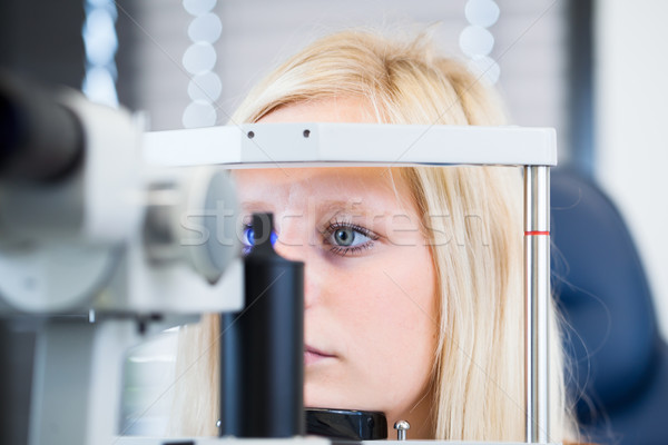 Pretty, young female patient having her eyes examined by an eye doctor Stock photo © lightpoet